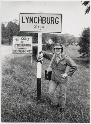 Primary view of object titled '[Junebug Clark leans on a sign for the city of Lynchburg, TN]'.