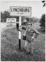 Thumbnail image of item number 1 in: '[Junebug Clark leans on a sign for the city of Lynchburg, TN]'.