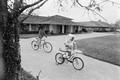 Photograph: [Angela and Dion Pride riding bicycles, 8]