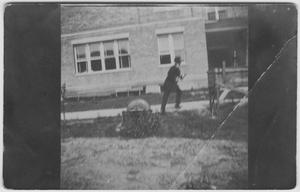 Primary view of object titled '[A man walking past a building]'.