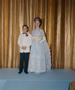 Photograph: [Boy and a woman in formal attire posing in front of a curtain backdr…