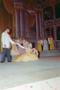 Photograph: [Woman sitting on a stage in a dress, gesturing towards a man]