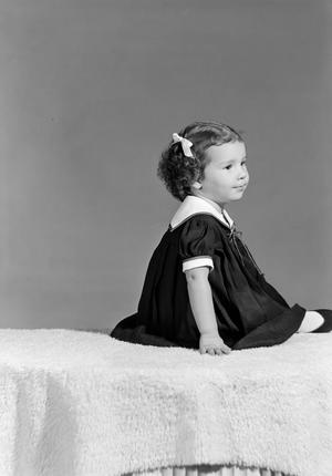 Primary view of object titled '[Little girl in a dress sitting on a fur blanket]'.