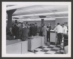 Primary view of object titled '[A crowd of people standing and talking around office desks]'.