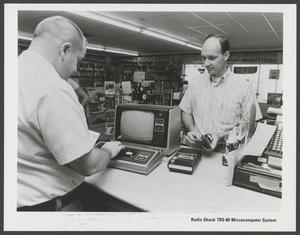 Primary view of object titled '[Advertisement featuring a store worker, a customer, and a computer]'.