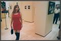 Photograph: [Woman in a red dress standing in a gallery]