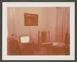 Photograph: [Room with a television, table, chairs and a framed photograph]
