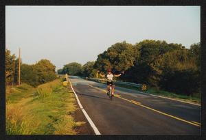 Primary view of object titled '[Cyclist riding no hands down a rural road: Lone Star Ride 2002 event photo]'.