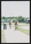 Photograph: [Two cyclists in matching jerseys riding into a park: Lone Star Ride …
