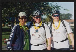 Primary view of object titled '[Three individuals posing together in the late afternoon: Lone Star Ride 2003 event photo]'.