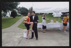 Primary view of object titled '[A cyclist posed comically with a mannequin dressed in black tie attire: Lone Star Ride 2010 event photo]'.