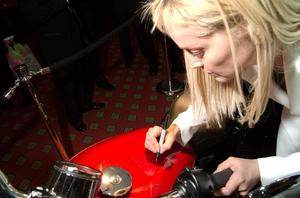 Primary view of object titled '[Sharon Stone autographs a motorcycle, 2005 Black Tie Dinner]'.