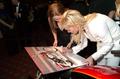 Photograph: [Sharon Stone autographs a poster, 2005 Black Tie Dinner]