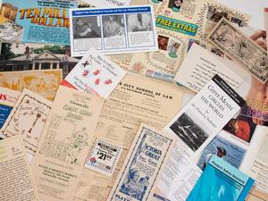 Closeup of a variety of scattered fliers, brochures, pamphlets and coupons from the James Flowers Collection of Ephemera Found in Returned Library Books.
