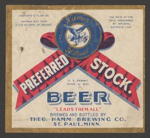 A Theodore Hamm Brewing Company Preferred Stock beer bottle label with an illustration of a blue and red ribbon and an image of an eagle carrying a medal in its beak. The red text below the illustration reads Leads Them All.