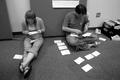 Photograph: [Nick Mosser and woman organize cards on the floor]