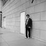 Photograph: [A man standing against a wall]