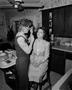 Photograph: [Woman gets makeup done in kitchen, 1]