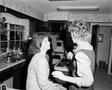 Photograph: [Woman gets makeup done in kitchen, 3]
