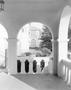 Photograph: [A patio of a building with an archway looking out]