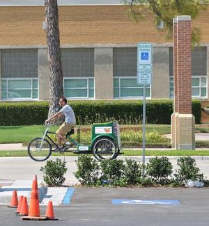 Primary view of object titled '[Pedicab driver passes Downtown Denton Transit Center]'.