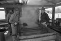 Primary view of [Hulen Wilcox and another man standing near the sugar cane evaporator]