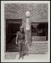 Photograph: [Man standing in front of a barber shop]
