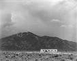 Photograph: [Adobe house silhouetted by a mountain]