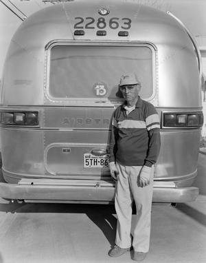 Primary view of object titled '[A man standing in front of the rear of an airstream]'.
