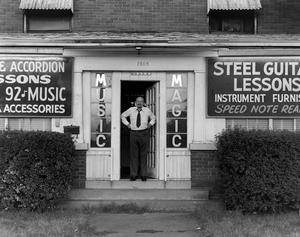 Primary view of object titled '[Claude Meadows posing in the doorway of "Music Magic"]'.