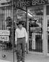 Photograph: [A man standing in front of the Peters Bros store]