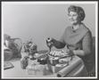 Primary view of [Julia Dell Hunter seated at a table of food]