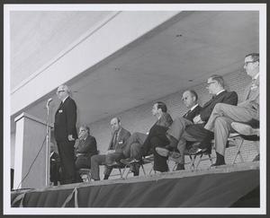 Primary view of [Photograph of a group of men sitting on a stage #1]