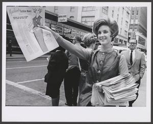 Primary view of object titled '[Photograph of a woman handing out Meacham's Fashion News]'.