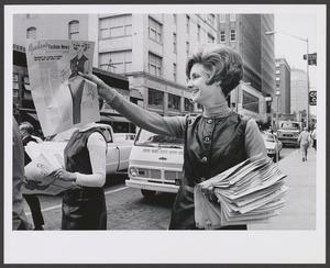 Primary view of object titled '[Photograph of a woman handing out Meacham's Fashion News, 2]'.