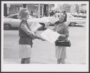 Primary view of object titled '[Photograph of a woman handing out a Meacham's Fashion magazine]'.