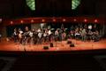 Primary view of [A group of percussionists and brass musicians performing on a stage]