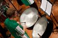 Photograph: [A man in a green shirt playing a set of drums]