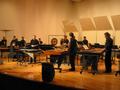 Photograph: [A group of percussionists in black playing xylophones and drums onst…