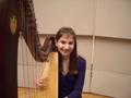 Photograph: [A girl in a purple dress sitting behind a harp]