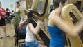 Photograph: [Three girls playing harps while two women talk]