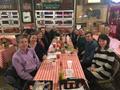 Photograph: [Two rows of people sitting at a table in a restaurant]