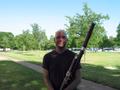 Photograph: [A man in a dark t-shirt and glasses posing with a bassoon]