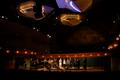 Primary view of [Thirteen jazz singers performing onstage under large light fixtures]