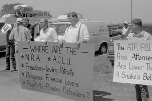 Primary view of object titled '[Three men holding signs at the Branch Davidian Annual Reunion]'.
