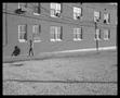 Photograph: [Man Walking Alongside a Brick Building]