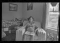 Photograph: [Elderly woman frowning and sitting in an armchair]