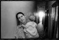 Photograph: [Woman holding a baby in an apartment hallway]