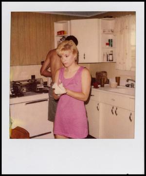 Primary view of object titled '[Woman wiping her hands in a kitchen]'.
