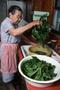 Primary view of [Preserving Traditions: An Old Woman Tending to Green Leafy Vegetables]